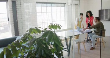 Ofisteki tasarım toplantısında projeyi tartışan ve dizüstü bilgisayarı kullanan çeşitli tasarımcılarla, yavaş çekim. Günlük ofis, iş, takım çalışması ve yaratıcı çalışma.