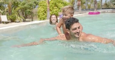 Yüzme havuzunda şişirilebilir yüzen mutlu beyaz bir aile. Tatil, boş zaman, yaz ve aile.