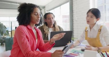 Ofisteki tasarım toplantısında projeyi tartışan ve dizüstü bilgisayarı kullanan çeşitli tasarımcılarla, yavaş çekim. Günlük ofis, iş, takım çalışması ve yaratıcı çalışma.