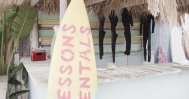 Sörf tahtaları ve sörf takımları kiralık sahil kulübesinde, ağır çekimde. Yaz, küçük işletmeler, hobiler ve tatiller.