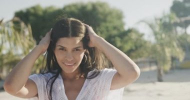 Güneşli sahilde dans eden, gülümseyen, ağır çekimde mutlu İspanyol kadının portresi. Yaz, dinlenme ve tatiller.