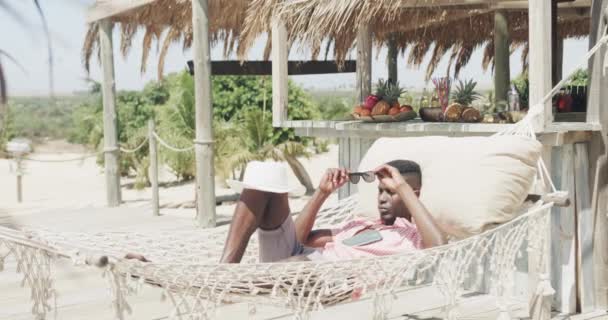 Hombre Afroamericano Feliz Acostado Hamaca Poniendo Sombrero Sobre Cara Playa — Vídeos de Stock