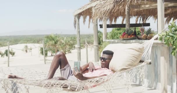 Szczęśliwy Afrykański Amerykanin Leżący Hamaku Robiący Selfie Telefonem Słonecznej Plaży — Wideo stockowe