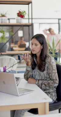 Akıllı telefondan ağır çekimde konuşan çift ırklı bir iş kadınının dikey videosu. İş, iş ve teknoloji.