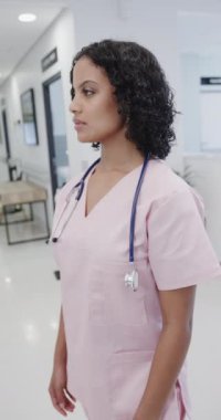 Hastanede ağır çekimde mutlu çift ırklı kadın doktorların dikey portresi. İlaç, sağlık ve bakım.