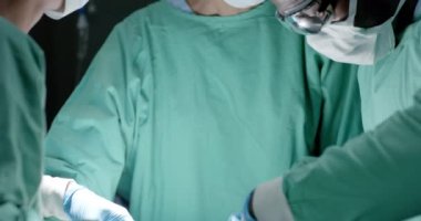 Ameliyathanede ağır çekimde ameliyat sırasında yüz maskesi takan çeşitli cerrahlar. İlaç, sağlık ve bakım.