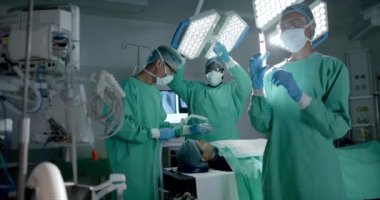 Ameliyathanede maskeli çeşitli cerrahlar ağır çekimde hastalara oksijen maskesi takıyor. İlaç, sağlık ve bakım.
