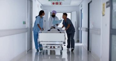 Çok sayıda doktor ve cerrahlar hastane yatağında ağır çekimde hastalarla yürüyorlar. İlaç, sağlık ve bakım.