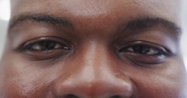 Kameraya yavaş çekimde bakan mutlu Afro-Amerikan bir adamın portresi. Yaşam tarzı ve özgüven.