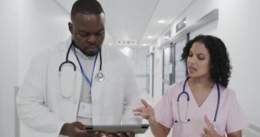 Farklı doktorlar tablet kullanıyor ve hastanede ağır çekimde konuşuyorlar. Tıp, sağlık, teknoloji ve bakım.