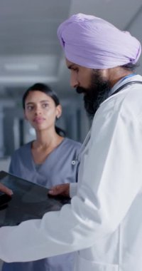 Doktorların doktorlarla konuştuğu ve röntgeni ağır çekimde tuttuğu dikey bir video. İlaç, sağlık ve bakım.