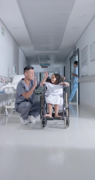 スローモーションで病院の女の子とアジア系男性外科医の高ファイビングの垂直ビデオ 健康とケア — ストック動画