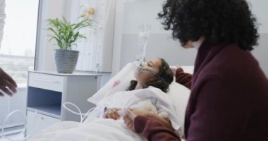 Çeşitli doktor ve ağır çekimde annesiyle birlikte oksijen maskesi takan hasta kız. İlaç, sağlık ve bakım.