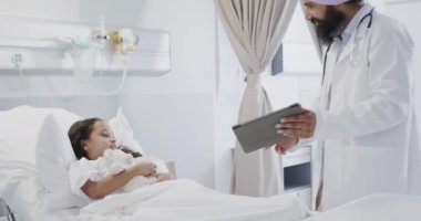 Hasta bir kızla birlikte ağır çekimde tablet kullanan mutlu çift ırklı doktor. Tıp, sağlık, teknoloji ve bakım.