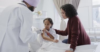 Çift ırklı doktor, hasta kız hastayı ve annesini ağır çekimde aşıladı. İlaç, sağlık ve bakım.