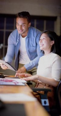 Çift ırklı iş adamlarının iş tartıştıkları, ofiste tablet kullandıkları dikey video, yavaş çekim. İş, takım çalışması, iletişim ve çalışma.