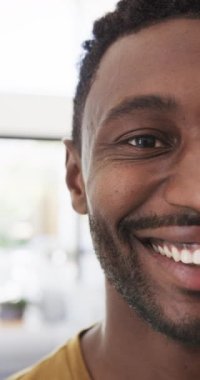 Mutlu Afro-Amerikan bir adamın evde ağır çekimde çekilmiş portresinin dikey videosu. Ev hayatı, yaşam tarzı ve özgüven..