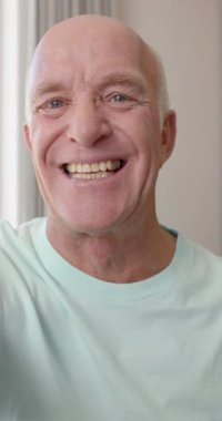 Kafkasyalı bir adamın yavaş çekimde videoya çekilen portresinin dikey videosu. Emeklilik, yaşam tarzı ve teknoloji.