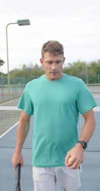 Ağır çekimde tenis raketiyle odaklanmış beyaz bir adamın dikey portresi. Spor, yaşam tarzı ve etkinlik.