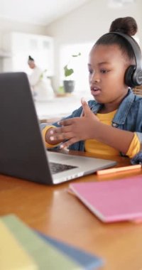 Mutlu Afrikalı Amerikalı bir kızın bilgisayarını yavaş çekimde online ders için kullanmasının dikey videosu. Yaşam tarzı, çocukluk, eğitim, öğrenme, iletişim ve ev hayatı.