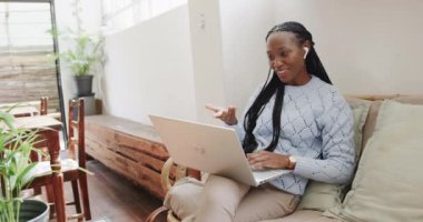 Kafede bilgisayarla video görüşmesi yapan mutlu Afro-Amerikan kadın, ağır çekimde. Yaşam tarzı, iletişim, girişimcilik ve yerel işletme.