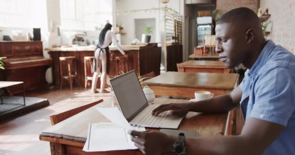 非裔美国人使用笔记本电脑和持有文件在咖啡店 慢动作 生活方式 创业和地方商业 — 图库视频影像
