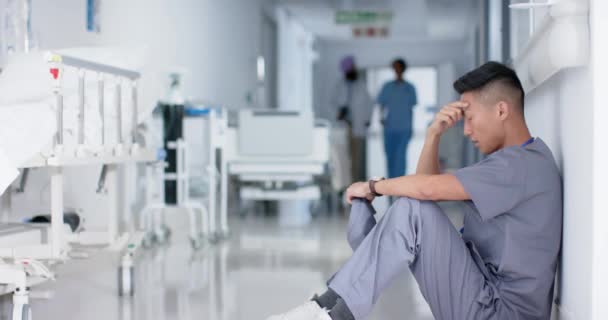 遅い動きで病院の壁に座っているストレスアジアの男性外科医 健康とケア — ストック動画