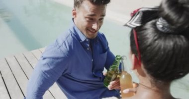 Kumsalın güneşli güvertesinde yavaş çekimde konuşan ve bira içen mutlu çift. Rahatlama, romantizm, tatiller ve yaşam tarzı.