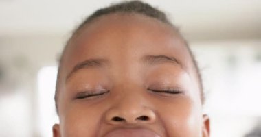 Afro-Amerikalı mutlu bir kızın portresi. Kameraya bakıyor ve gülümsüyor. Ağır çekimde. Yaşam tarzı, çocukluk, mutluluk ve ev hayatı.