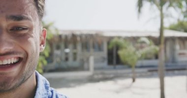 Güneşli sahilde, fotokopi uzayı ile ağır çekimde gülümseyen mutlu melez bir adamın yarım portresi. Rahatlama, tatiller ve yaşam tarzı.