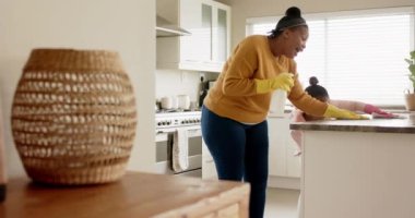 Mutlu Afro-Amerikan anne ve kızı mutfak tezgahını temizliyor, yavaş çekim, fotokopi odası. Yaşam tarzı, birliktelik, aile ve aile hayatı..