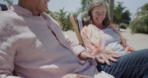 幸せな高齢者の白人のカップルデッキチェアに日当たりの良いビーチで ゆっくりとした動きで話して座っている リラクゼーション シニアライフスタイル — ストック動画