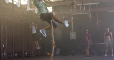 İp tırmanmada ağır çekimde çift ırklı adam eğitimi. Sağlıklı yaşam tarzı, çapraz eğitim, fitness, güç ve egzersiz.