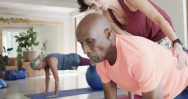 Farklı son sınıflar pilates sınıfında kadın koçla egzersiz toplarını yavaş çekimde kullanıyor. Egzersiz, emeklilik ve sağlıklı bir yaşam tarzı..