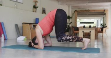 Pilates stüdyosunda, ağır çekimde değişmeden paspas üzerinde egzersiz yapan son sınıf beyaz kadın. Egzersiz, emeklilik ve sağlıklı bir yaşam tarzı..