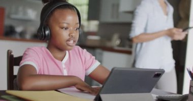 Afro-Amerikalı kız tablet kullanıyor ve ödev yapıyor, ağır çekimde. Yaşam tarzı, iletişim, öğrenme, çocukluk ve ev hayatı.