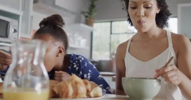 Mutlu Afro-Amerikan anne ve kızları kahvaltılarını mutfakta yavaş çekimde yiyor. Yaşam tarzı, aile ve aile hayatı.