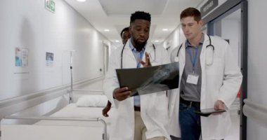 Ciddi çeşitlilikte erkek ve kadın doktorlar röntgen ışınlarıyla konuşuyor ve yürüyorlar, değişmeden. Sağlık, ilaç ve hastane koridoru..