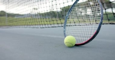 Tenis raketini ve topunu açık tenis kortunda kaleye yakın tut, ağır çekimde. Spor, rekabet, yaşam tarzı, eğlence ve etkinlik.