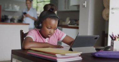 Afro-Amerikalı kız tablet kullanıyor ve ödev yapıyor, ağır çekimde. Yaşam tarzı, iletişim, öğrenme, çocukluk ve ev hayatı.