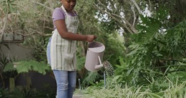 Mutlu Afro-Amerikan kızları bahçede çiçek suluyor, ağır çekimde. Yaşam tarzı, hobiler, çocukluk ve ev hayatı.