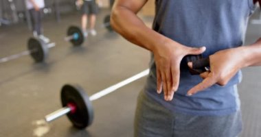 Spor salonunda ağırlık çalışmasından önce parmaklarını bağlayan melez bir adamın orta kısmı. Ağır çekimde. Sağlıklı yaşam tarzı, ağırlık çalışması, spor, güç ve egzersiz.