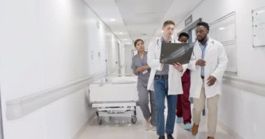 Ciddi çeşitlilikte erkek ve kadın doktorlar röntgen ışınlarıyla konuşuyor ve yürüyorlar, değişmeden. Sağlık, ilaç ve hastane koridoru..