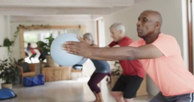 Farklı yaşlılara odaklanarak ağır çekimde, değişmeden pilates sınıfında top tutuyorlar. Egzersiz, emeklilik ve sağlıklı bir yaşam tarzı..