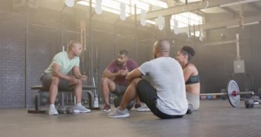 Spor salonundaki beden eğitimi dersinden sonra yavaş çekimde çeşitli gruplar halinde mutlu bir şekilde oturun ve konuşun. Sağlıklı yaşam tarzı, çapraz eğitim, arkadaşlık, fitness ve egzersiz.