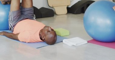 Farklı son sınıflar pilates sınıfında kadın koçla egzersiz toplarını yavaş çekimde kullanıyor. Egzersiz, emeklilik ve sağlıklı bir yaşam tarzı..