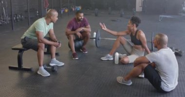 Spor salonundaki beden eğitimi dersinden sonra yavaş çekimde çeşitli gruplar halinde mutlu bir şekilde oturun ve konuşun. Sağlıklı yaşam tarzı, çapraz eğitim, arkadaşlık, fitness ve egzersiz.