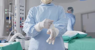 Yüzü maskeli çeşitli erkek ve kadın cerrahlar ağır çekimde tıbbi eldiven takıyor, değiştirilmemiş. Sağlık, ilaç ve hastane tiyatrosu..