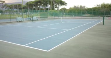 Ağaçlarla çevrili boş tenis kortunun genel manzarası, yavaş çekim. Spor, tenis, yaşam tarzı, rekabet, eğlence ve etkinlik.