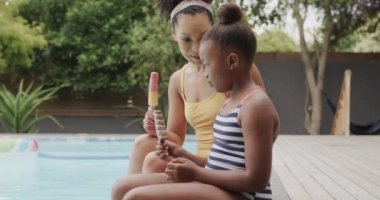 Mutlu Afro-Amerikan anne ve kızı yüzme havuzunda dondurma yiyor, ağır çekimde. Yaşam tarzı, aile ve aile hayatı.